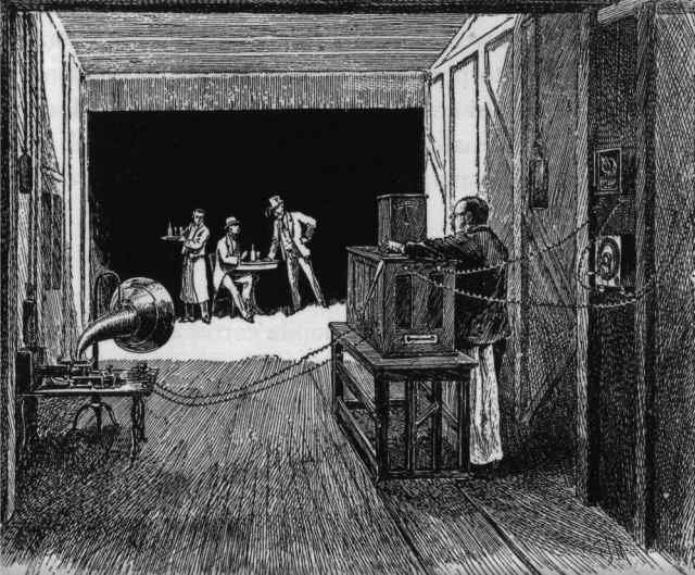 Engraving of a dark wooden studio interior where a man operates a large boxy camera pointed at performers lit by daylight.
