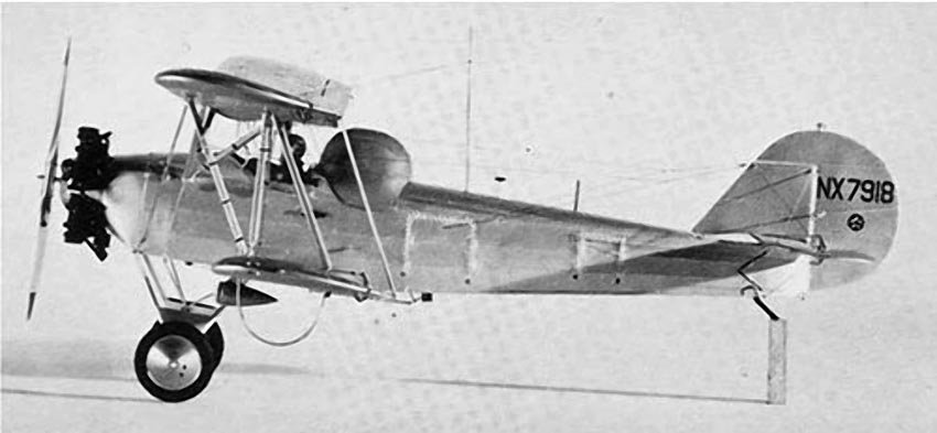 A small biplane on the ground with the rear cockpit completely covered by a hood.