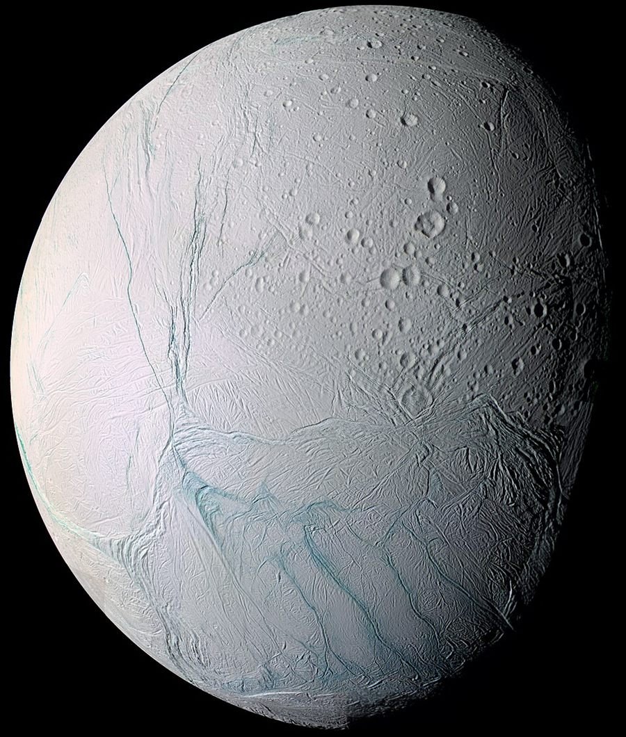 Photograph of a bright icy moon covered in craters and long blue fracture lines, against black space.