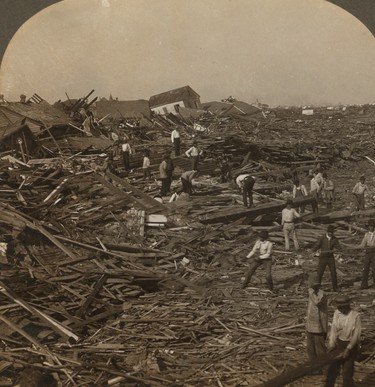 Sepia photograph of men searching an enormous field of splintered timber and wreckage.