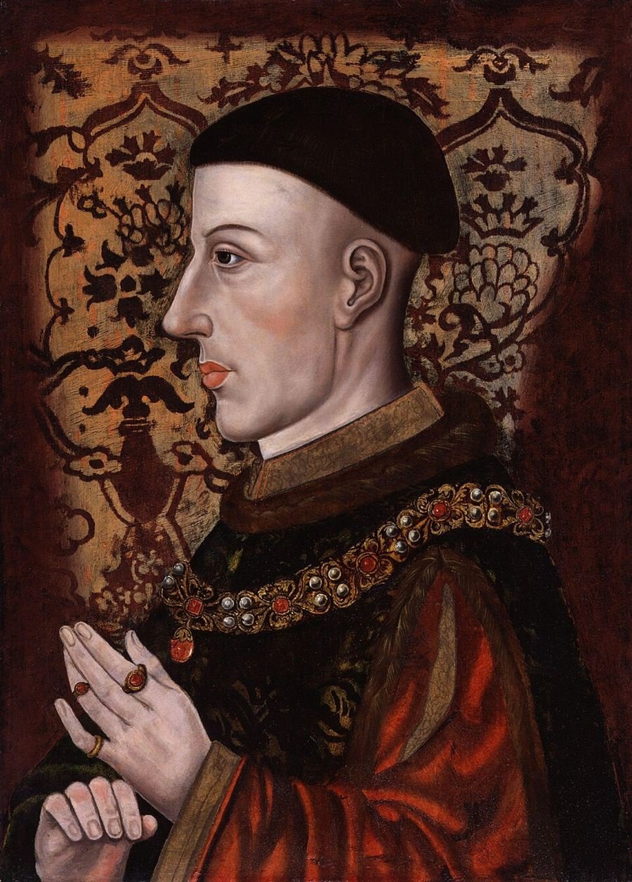 Medieval profile portrait of a young king in a dark cap and red and gold robes, hands raised in prayer.